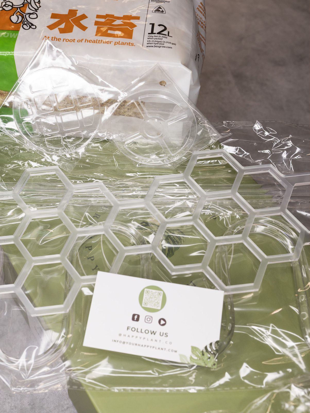 A flat lay of Your Happy Plant supplies — propagation inserts, a honeycomb trellis, and spagmoss